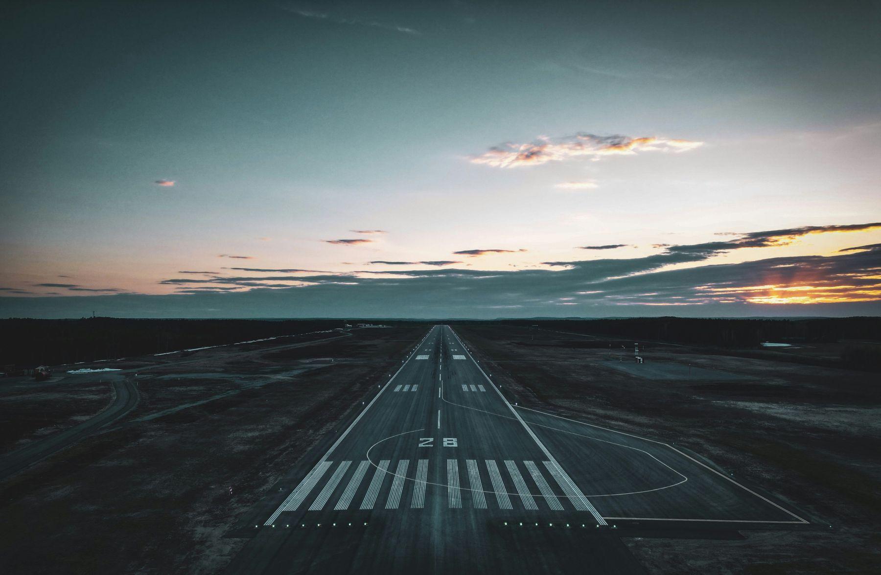 Runway 28 at dusk, centreline receding to the horizon. Skellefteå Airport.