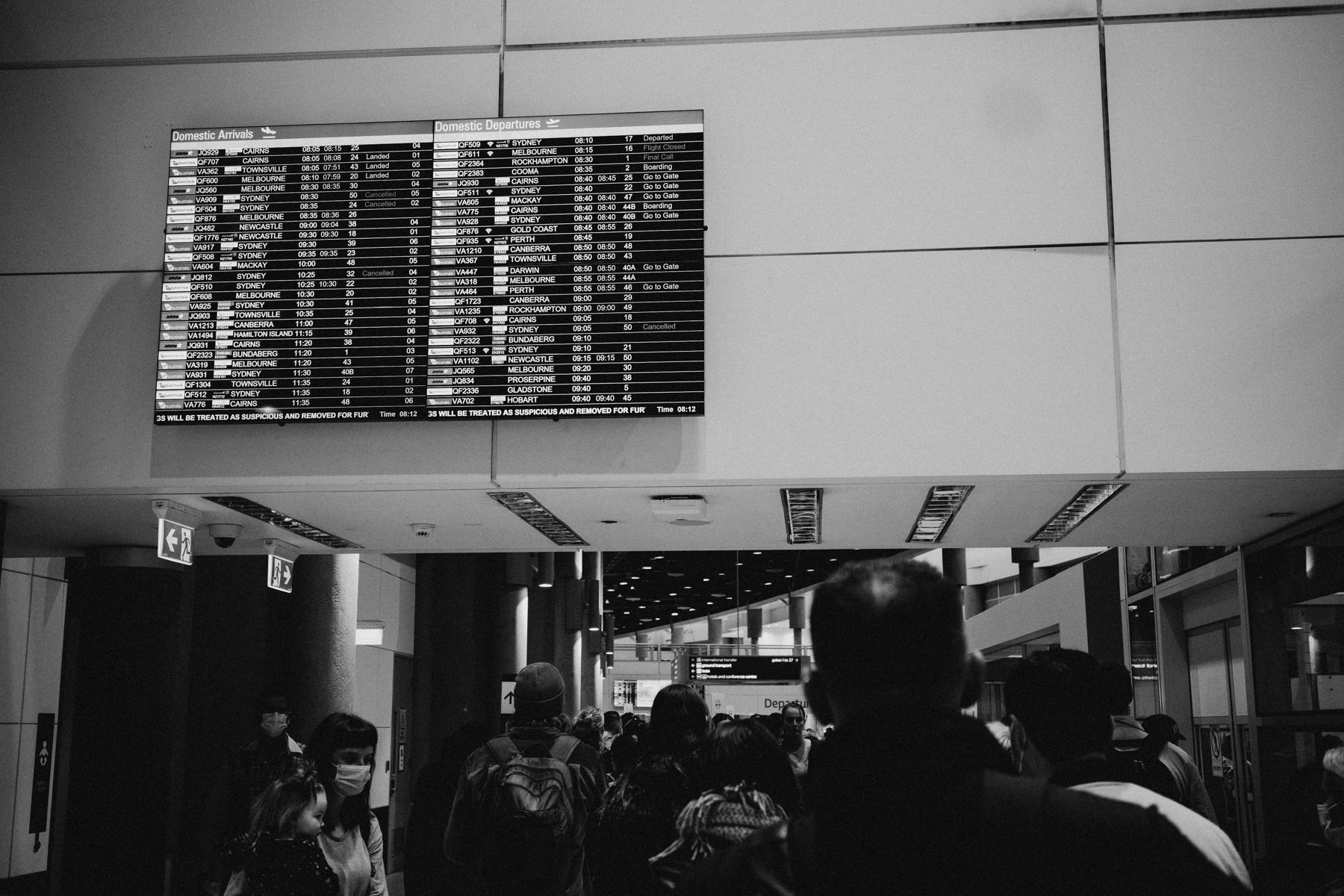 Departures board above a crowd seen from behind, Brisbane Airport